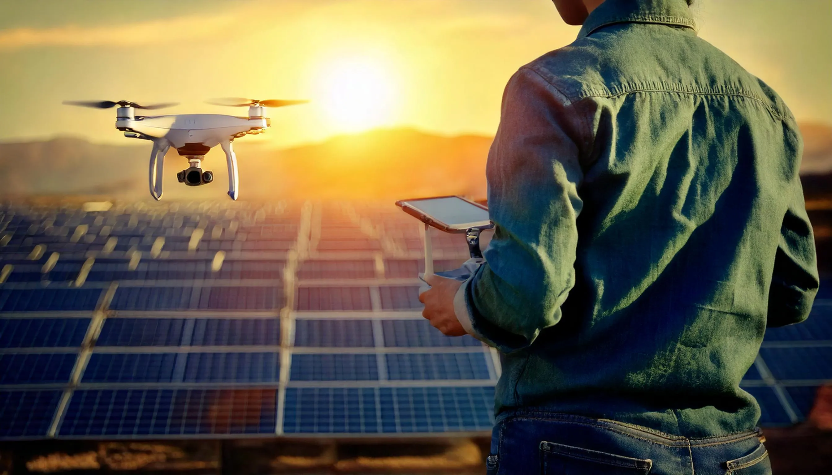 Operador manejando un dron en un parque solar para inspección de instalaciones.