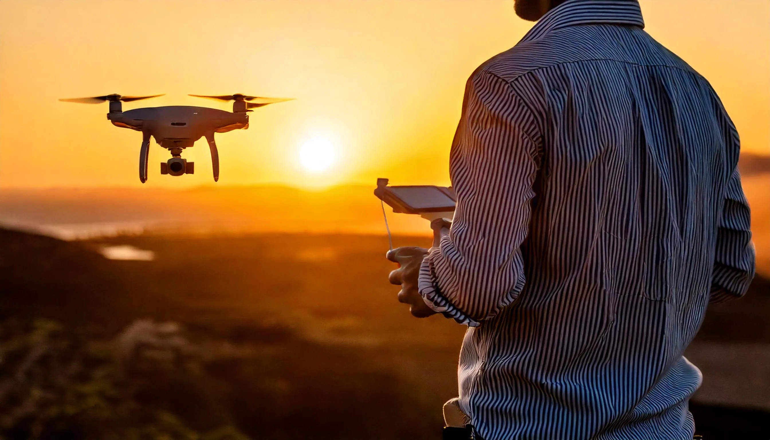 Operador y dron capturando datos al atardecer en una operación aérea.